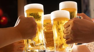 Personen stoßen mit Bierglaesern gemeinsam an