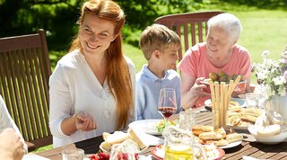 Familie sitzt glücklich am Tisch im Garten 