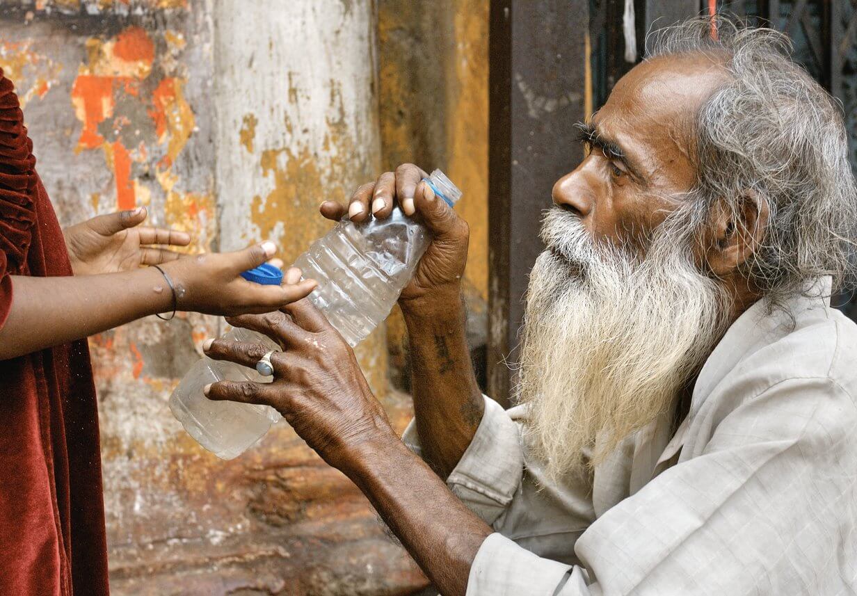 Älterer Herr bekommt eine Plastikflasche mit Wasser gereicht