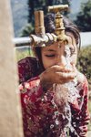 Mädchen trinkt frisches Wasser in Nepal